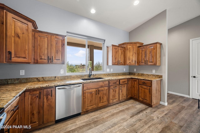 kitchen with light stone countertops, light wood-type flooring, stainless steel dishwasher, and sink