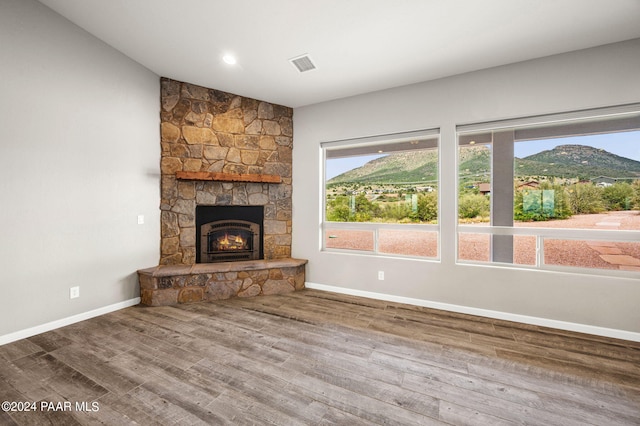 unfurnished living room featuring hardwood / wood-style flooring, a mountain view, and a fireplace