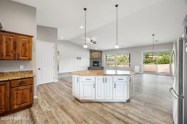 kitchen with light wood-type flooring, stainless steel fridge, a center island, and lofted ceiling