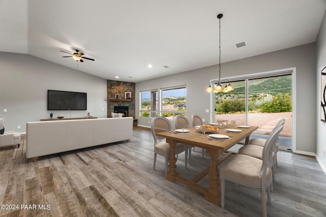 dining room with a fireplace, hardwood / wood-style flooring, vaulted ceiling, and a wealth of natural light