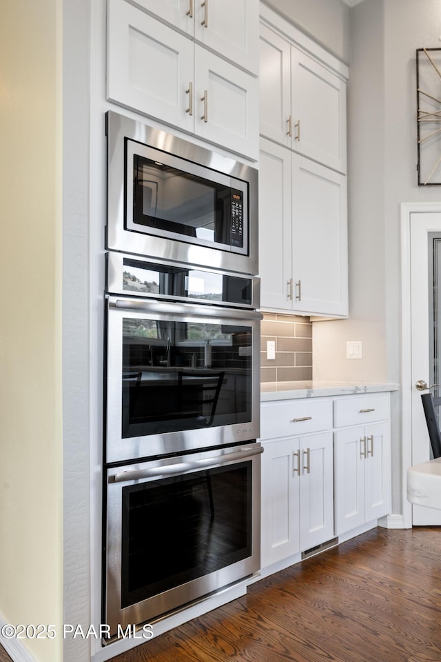 kitchen featuring light countertops, stainless steel appliances, dark wood finished floors, backsplash, and white cabinets