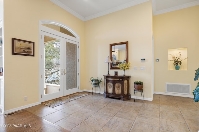 foyer entrance with ornamental molding, baseboards, and visible vents