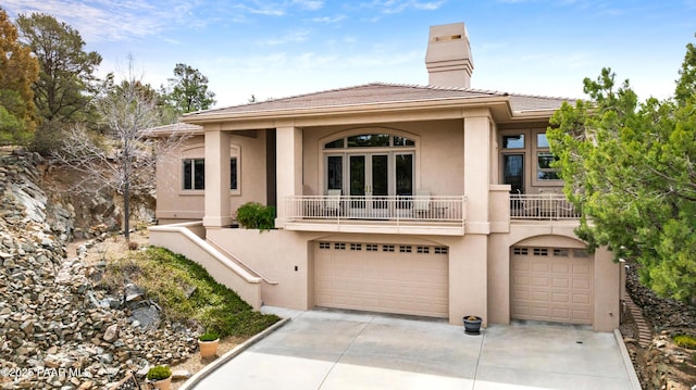 view of front of home with stucco siding, a chimney, a garage, and concrete driveway