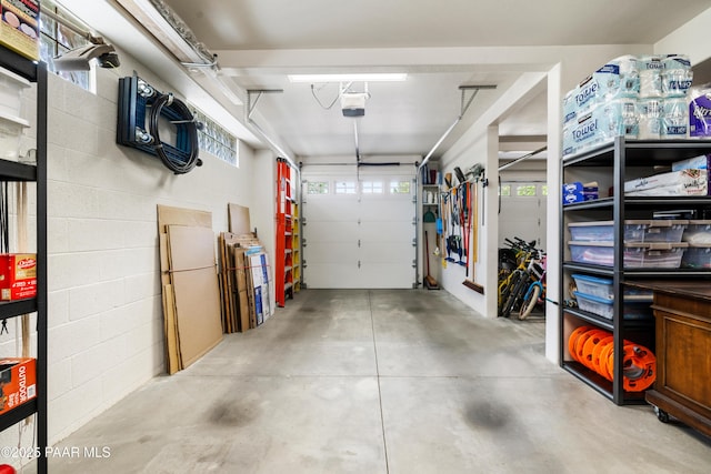garage featuring a garage door opener and concrete block wall