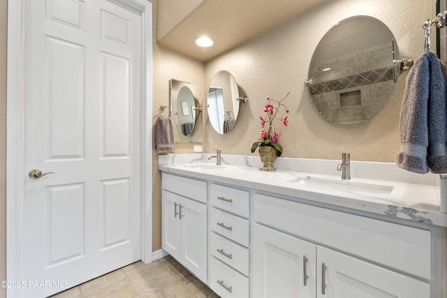bathroom with double vanity, a sink, and a textured wall