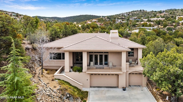 view of front of property featuring stucco siding, an attached garage, a chimney, and a tiled roof