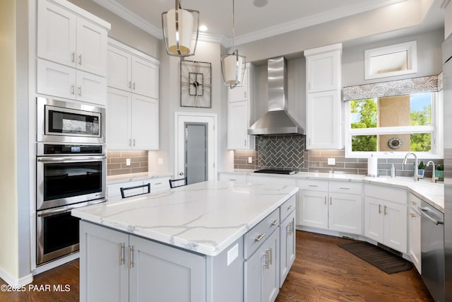 kitchen with wall chimney range hood, white cabinetry, and appliances with stainless steel finishes