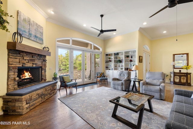 living area with a fireplace, wood finished floors, a ceiling fan, and ornamental molding
