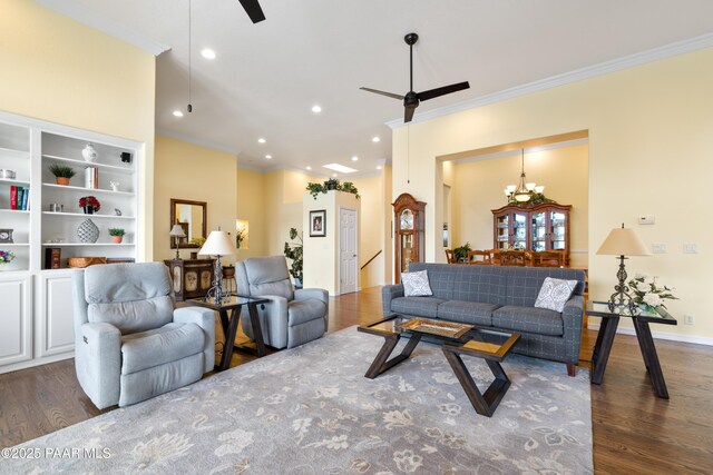 living area featuring recessed lighting, ornamental molding, ceiling fan with notable chandelier, and dark wood finished floors