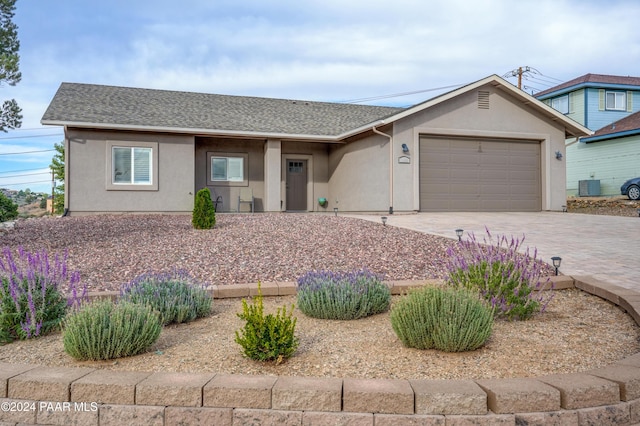 single story home featuring central AC unit and a garage