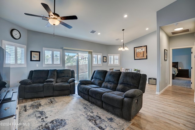 living room with vaulted ceiling, light hardwood / wood-style floors, and ceiling fan with notable chandelier