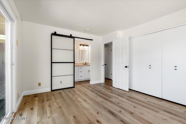 902 Fern Dr, Prescott, AZ 86305 - unfurnished bedroom with a barn door, light wood-style flooring, baseboards, and a closet