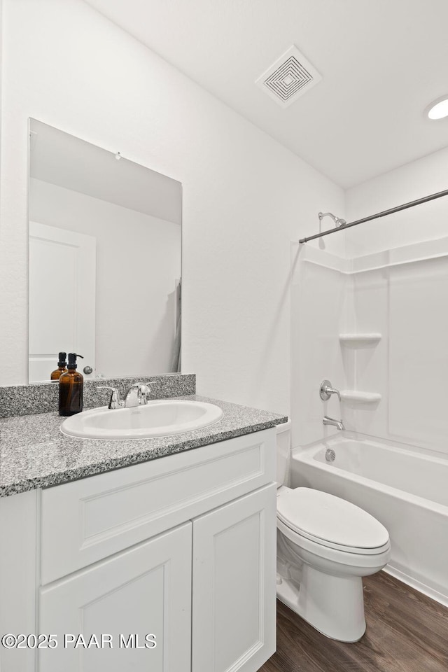 full bathroom featuring vanity, hardwood / wood-style floors, washtub / shower combination, and toilet