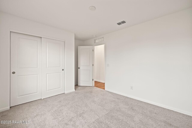 unfurnished bedroom featuring a closet and light colored carpet