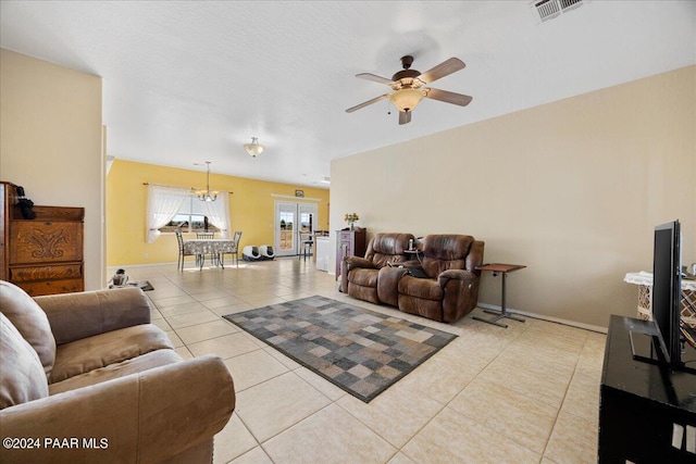 tiled living room featuring french doors and ceiling fan with notable chandelier