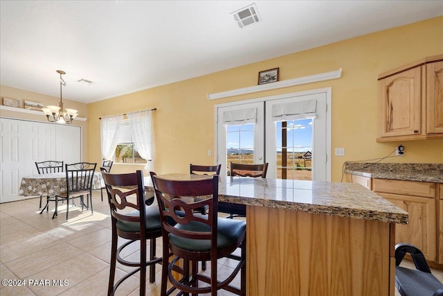 kitchen with plenty of natural light, light tile patterned floors, hanging light fixtures, and a notable chandelier