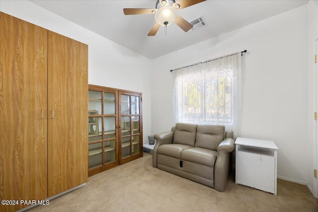 living area with light carpet and ceiling fan