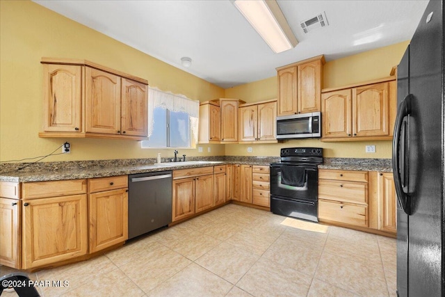 kitchen featuring dark stone counters, sink, black appliances, light brown cabinets, and light tile patterned flooring