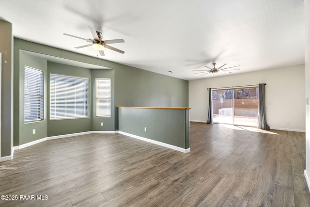 spare room featuring dark wood-type flooring, ceiling fan, and a healthy amount of sunlight