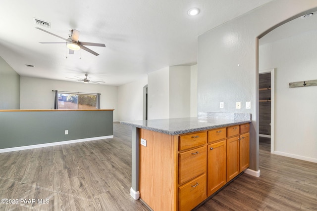 kitchen featuring ceiling fan, dark hardwood / wood-style flooring, and light stone countertops