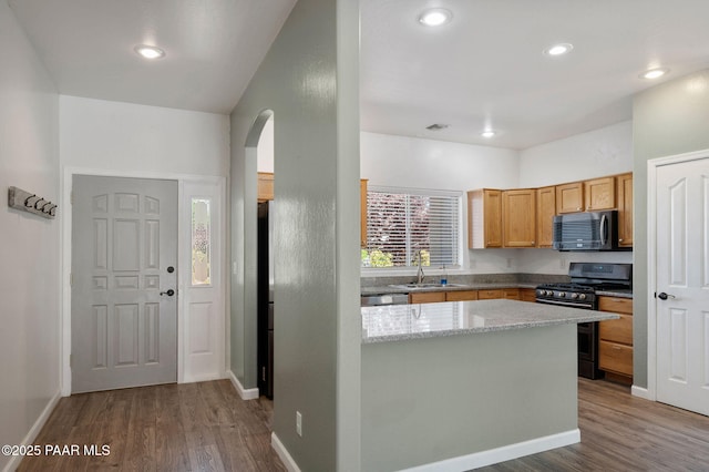 kitchen featuring hardwood / wood-style flooring, appliances with stainless steel finishes, and light stone counters