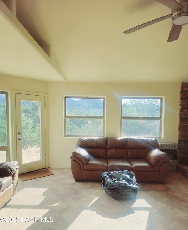 living room with heating unit, ceiling fan, healthy amount of natural light, and vaulted ceiling