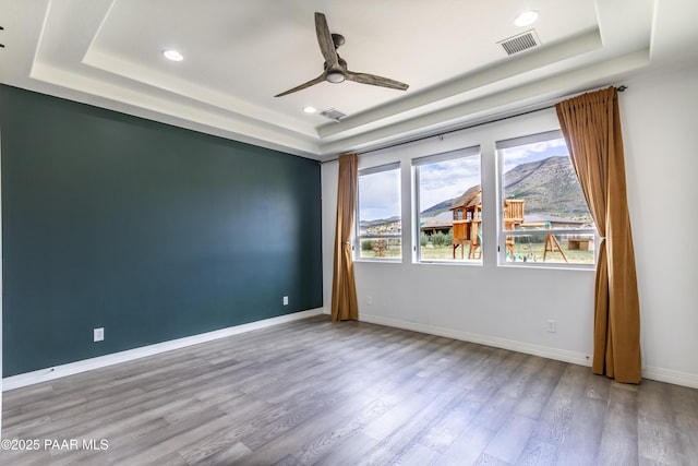 spare room with wood finished floors, visible vents, recessed lighting, a ceiling fan, and a raised ceiling