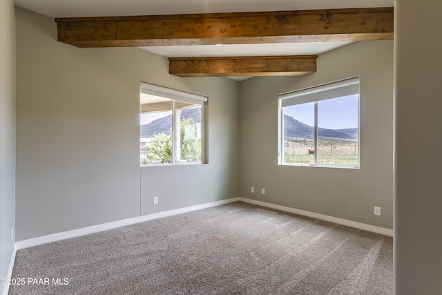 carpeted spare room with baseboards, a wealth of natural light, and beam ceiling