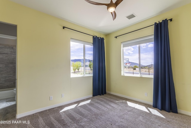 empty room with a wealth of natural light, carpet flooring, and visible vents