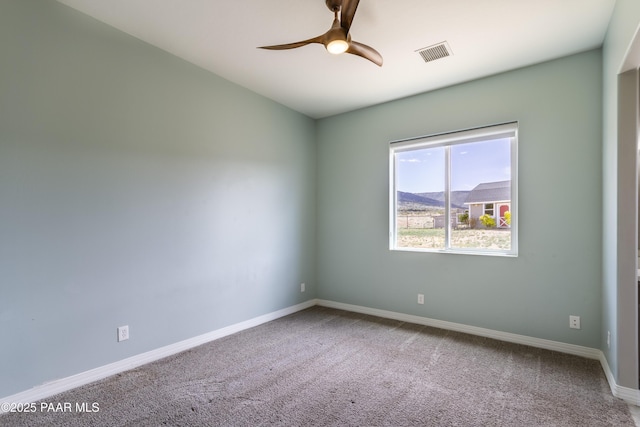 empty room featuring ceiling fan, carpet floors, baseboards, and visible vents