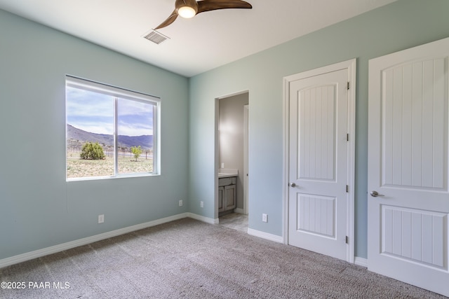 unfurnished bedroom featuring a mountain view, visible vents, baseboards, light colored carpet, and ensuite bath