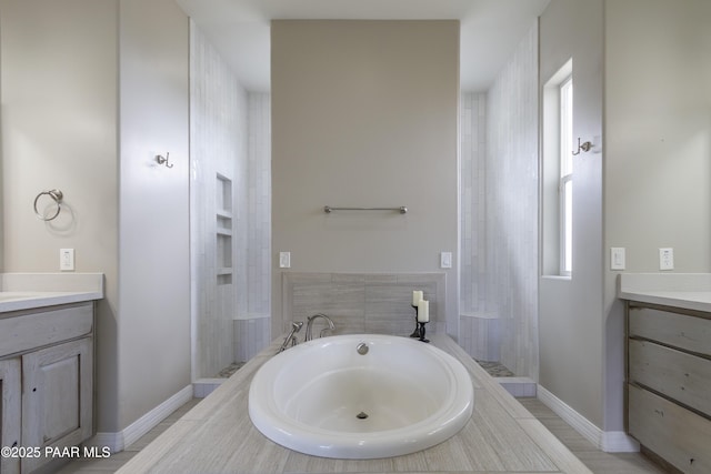 full bath featuring a garden tub, baseboards, vanity, and a tile shower