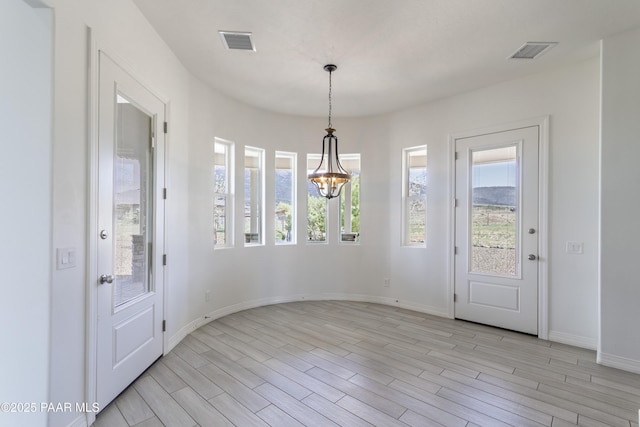 interior space featuring an inviting chandelier, light wood-style floors, and visible vents