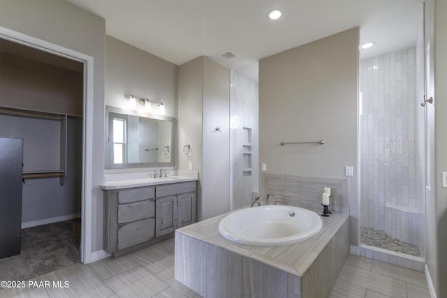 full bathroom featuring a garden tub, a tile shower, baseboards, vanity, and recessed lighting