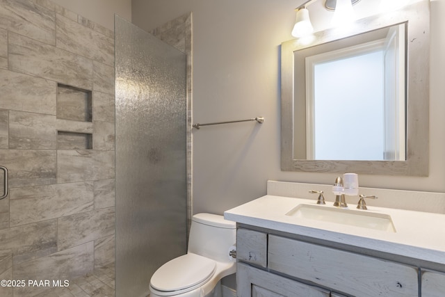 bathroom featuring vanity, toilet, and tiled shower