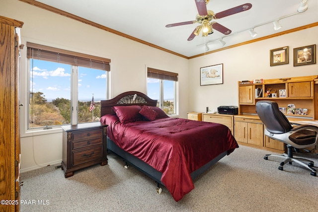 bedroom featuring rail lighting, baseboards, light colored carpet, and crown molding
