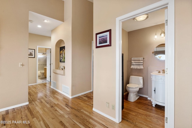 bathroom featuring vanity, toilet, wood finished floors, and baseboards