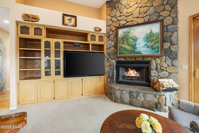carpeted living room featuring a stone fireplace