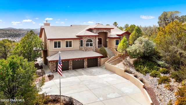 view of front of property with stucco siding, a chimney, a garage, stone siding, and driveway