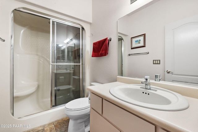 full bath featuring stone finish flooring, toilet, a stall shower, and vanity
