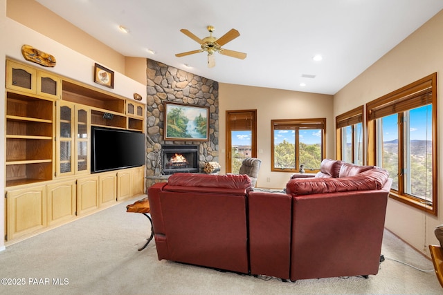 carpeted living room featuring a stone fireplace, vaulted ceiling, recessed lighting, and a ceiling fan