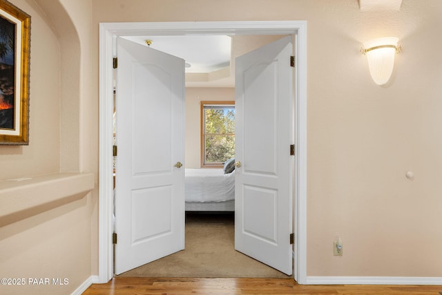 corridor with baseboards and light wood-type flooring
