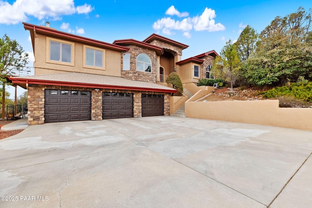 view of front of home with stucco siding, stone siding, concrete driveway, and an attached garage