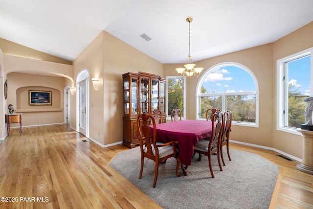 dining room featuring a chandelier, visible vents, light wood finished floors, and vaulted ceiling