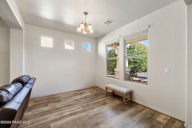 unfurnished room featuring hardwood / wood-style floors, a textured ceiling, and a notable chandelier