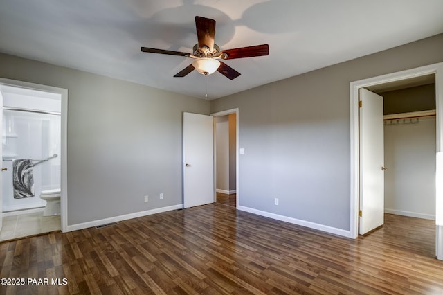 unfurnished bedroom featuring ensuite bathroom, dark hardwood / wood-style floors, ceiling fan, and a closet