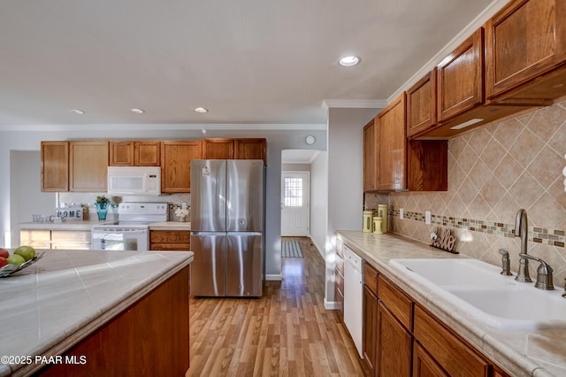 kitchen featuring sink, decorative backsplash, light hardwood / wood-style floors, crown molding, and white appliances