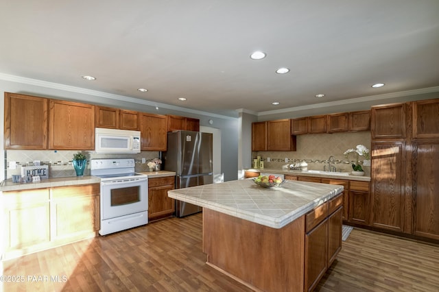 kitchen with a kitchen island, hardwood / wood-style floors, tile countertops, sink, and white appliances