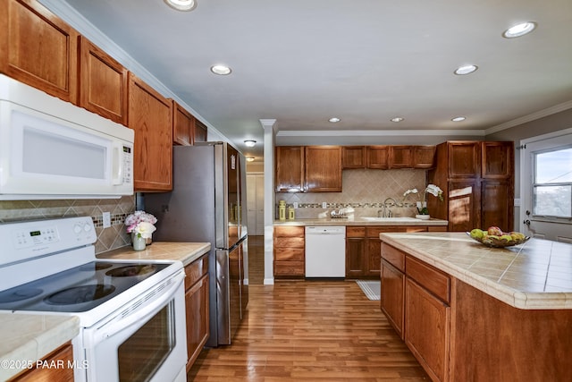 kitchen with sink, crown molding, white appliances, light hardwood / wood-style flooring, and backsplash