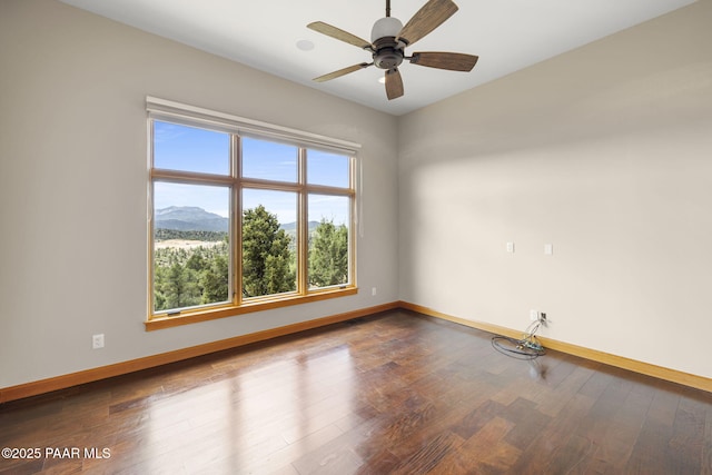 spare room with hardwood / wood-style flooring, a mountain view, and ceiling fan